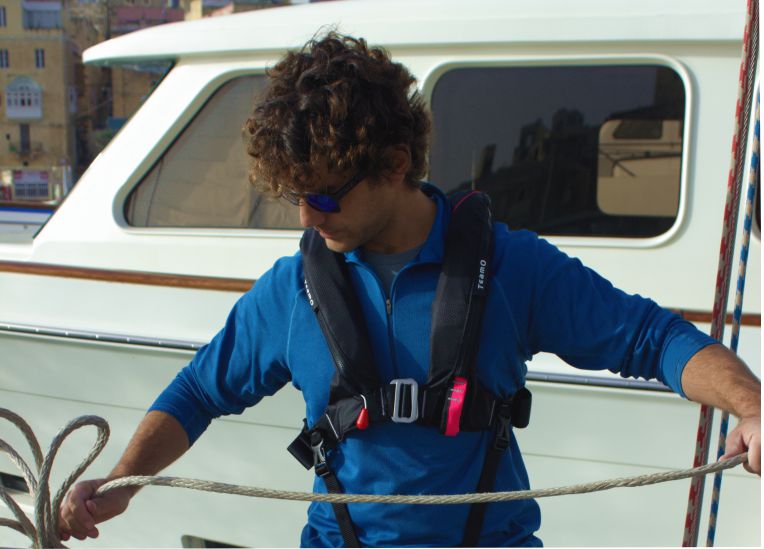TeamO Coastal BackTow Lifejacket in Black worn on deck whilst coiling a rope by a sailor